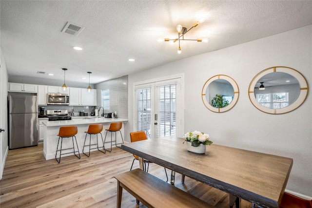 3814 Seabrook St, Houston, TX 77021 - dining space featuring light wood-style floors, recessed lighting, a chandelier, a textured ceiling, and french doors
