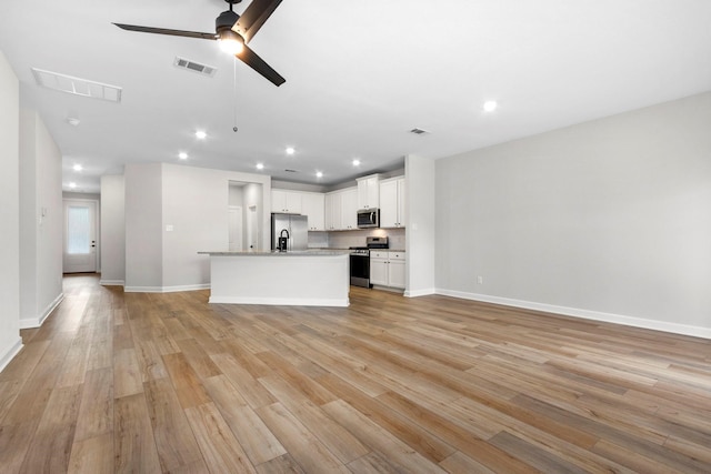 910 Whispering Winds Dr, Beasley, TX 77417 - kitchen featuring appliances with stainless steel finishes, open floor plan, light wood-type flooring, a center island with sink, and recessed lighting