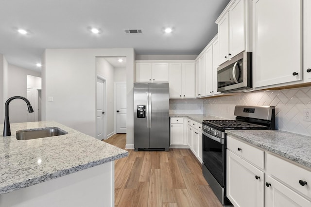 910 Whispering Winds Dr, Beasley, TX 77417 - kitchen featuring appliances with stainless steel finishes, a sink, white cabinets, and recessed lighting