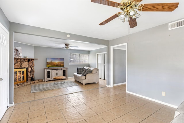 7730 Wickersham Pl, Beaumont, TX 77706 - living area with ceiling fan, light tile patterned floors, baseboards, and a stone fireplace