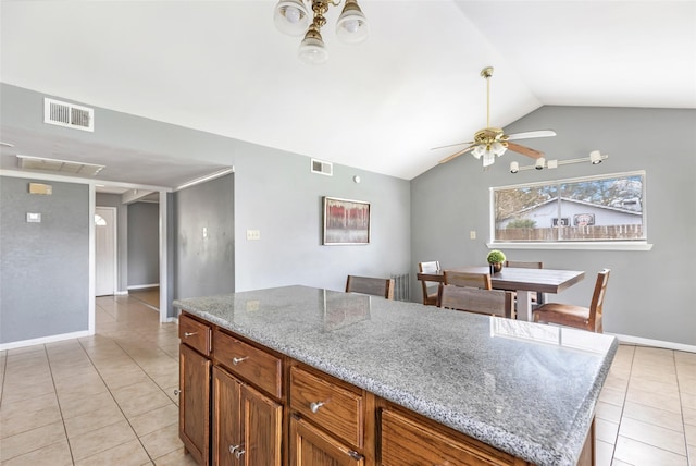 7730 Wickersham Pl, Beaumont, TX 77706 - kitchen with light tile patterned floors, vaulted ceiling, ceiling fan, baseboards, and light stone counters