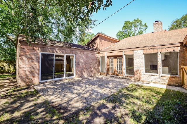 rear view of house with a patio area, a chimney, and brick siding