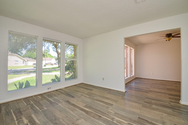 empty room with wood finished floors, a ceiling fan, and baseboards