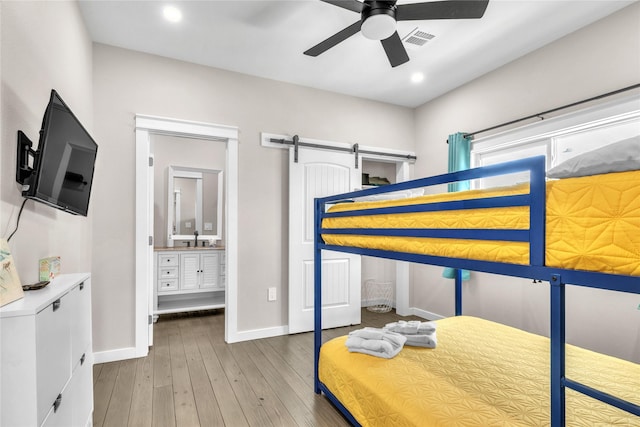 1079 Cedar Ln, Gilchrist, TX 77617 - bedroom featuring a sink, a barn door, baseboards, hardwood / wood-style flooring, and recessed lighting