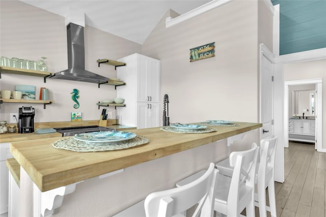 1079 Cedar Ln, Gilchrist, TX 77617 - kitchen featuring butcher block counters, open shelves, wall chimney exhaust hood, white cabinets, and lofted ceiling