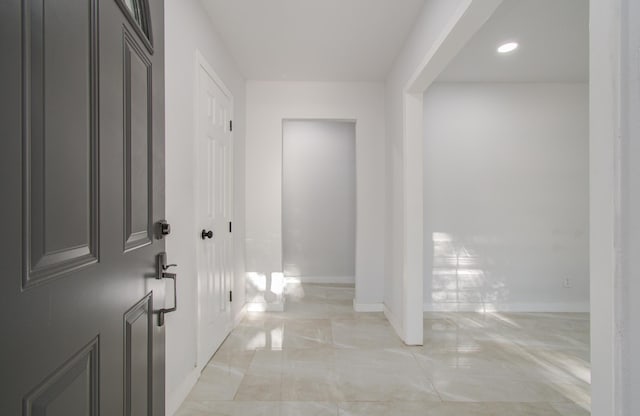 corridor featuring light marble finish floors, baseboards, and recessed lighting