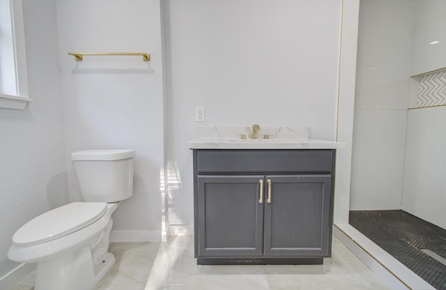 bathroom featuring toilet, vanity, a shower, and baseboards