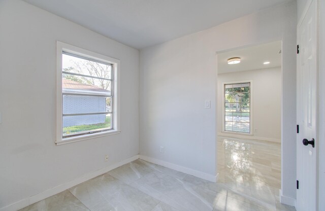 spare room with baseboards and light marble finish floors