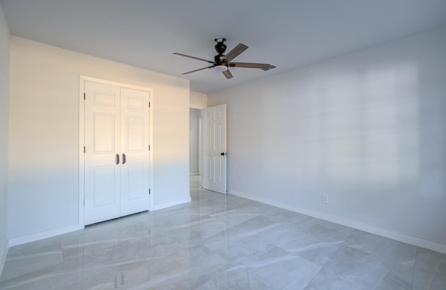 unfurnished bedroom featuring baseboards, light marble finish flooring, and a ceiling fan