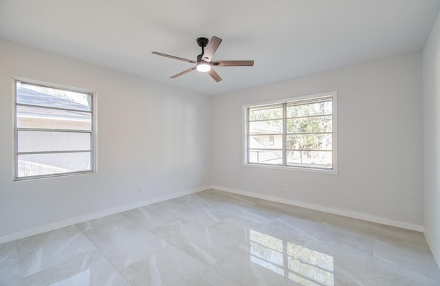 empty room with ceiling fan and baseboards