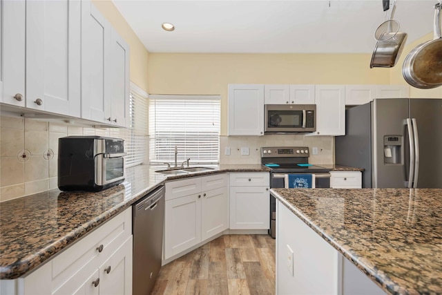 17906 Camden Oaks Ln, Richmond, TX 77407 - kitchen with appliances with stainless steel finishes, a sink, white cabinetry, light wood-style flooring, and recessed lighting