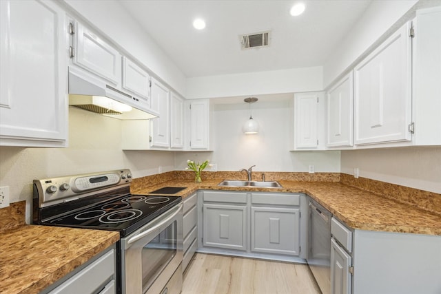 2515 Bering Dr Unit 11, Houston, TX 77057 - kitchen featuring stainless steel appliances, under cabinet range hood, light wood-style floors, white cabinetry, and recessed lighting