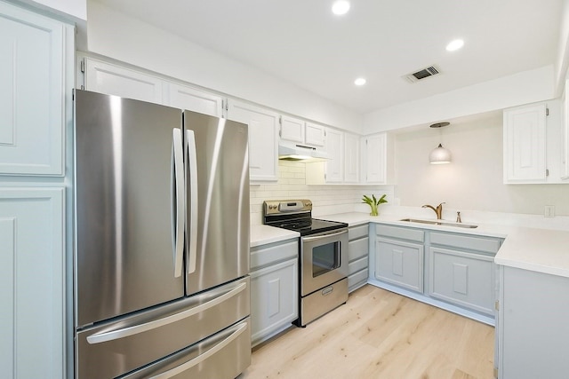 2515 Bering Dr Unit 11, Houston, TX 77057 - kitchen featuring appliances with stainless steel finishes, under cabinet range hood, light wood-type flooring, light countertops, and decorative backsplash