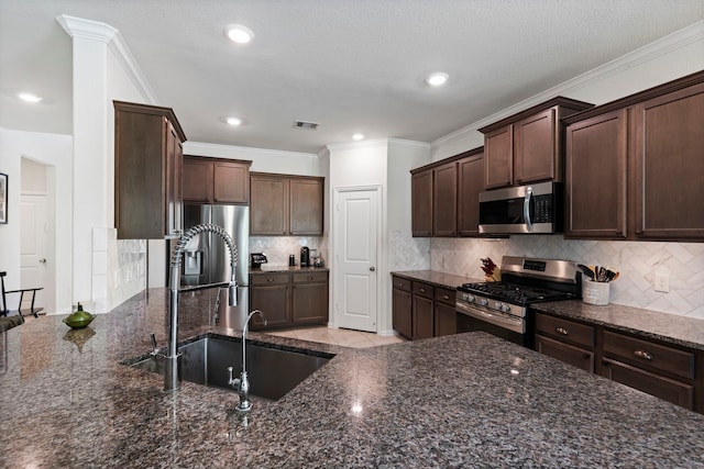 315 Cadela Dr, Montgomery, TX 77316 - kitchen featuring appliances with stainless steel finishes, a sink, dark brown cabinetry, tasteful backsplash, and dark stone countertops