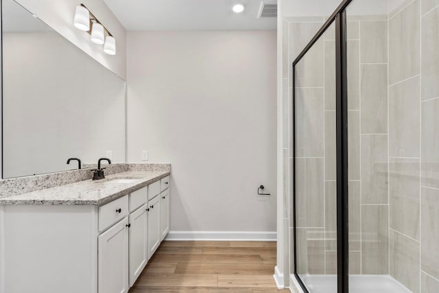 bathroom with a stall shower, wood finished floors, vanity, and baseboards