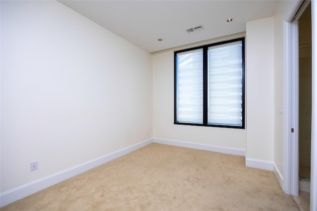 spare room featuring light carpet and baseboards