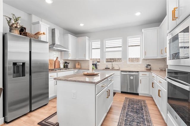 21811 Gibson Desert Dr, Cypress, TX 77433 - kitchen featuring stainless steel appliances, wall chimney exhaust hood, a sink, a center island, and white cabinets