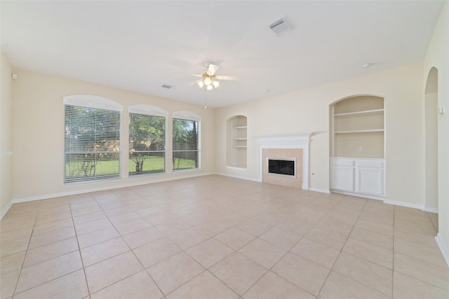 12236 S Shadow Cove Dr, Houston, TX 77082 - unfurnished living room featuring built in shelves, a ceiling fan, light tile patterned flooring, a high end fireplace, and baseboards
