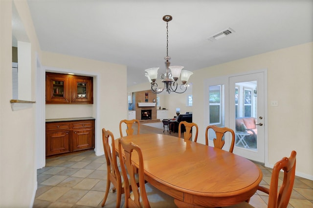 2810 Cottonwood Dr, Katy, TX 77493 - dining space featuring light tile patterned floors, a chandelier, and a lit fireplace