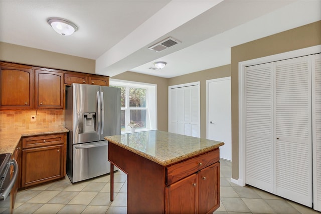 2810 Cottonwood Dr, Katy, TX 77493 - kitchen featuring appliances with stainless steel finishes, light tile patterned floors, decorative backsplash, light stone countertops, and brown cabinetry