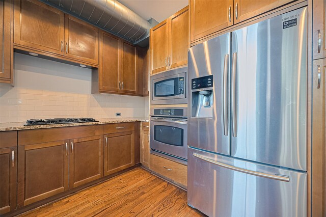 5005 Hidalgo St Unit 410, Houston, TX 77056 - kitchen featuring appliances with stainless steel finishes, light wood-type flooring, tasteful backsplash, and light stone counters