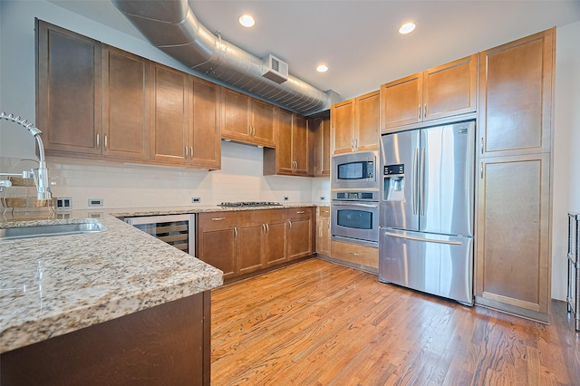 5005 Hidalgo St Unit 410, Houston, TX 77056 - kitchen with stainless steel appliances, a sink, beverage cooler, light wood-style floors, and tasteful backsplash