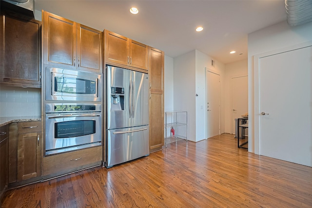 5005 Hidalgo St Unit 410, Houston, TX 77056 - kitchen with appliances with stainless steel finishes, dark wood-style floors, recessed lighting, light stone counters, and backsplash
