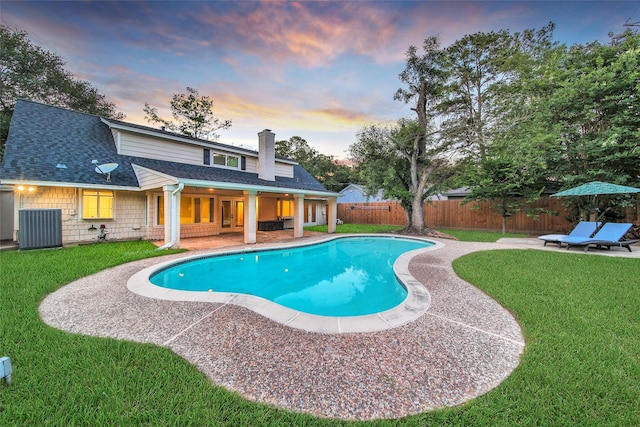 pool at dusk with central AC unit and a patio