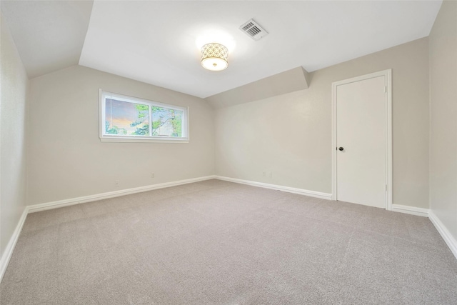spare room with vaulted ceiling, carpet flooring, and baseboards