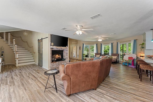 4701 County Road 747a, Brazoria, TX 77422 - living area featuring light wood-type flooring, ceiling fan, a textured ceiling, stairs, and a brick fireplace