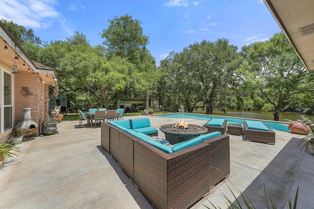 4701 County Road 747a, Brazoria, TX 77422 - view of patio / terrace with an outdoor living space with a fire pit, view of scattered trees, an outdoor pool, and outdoor dining space