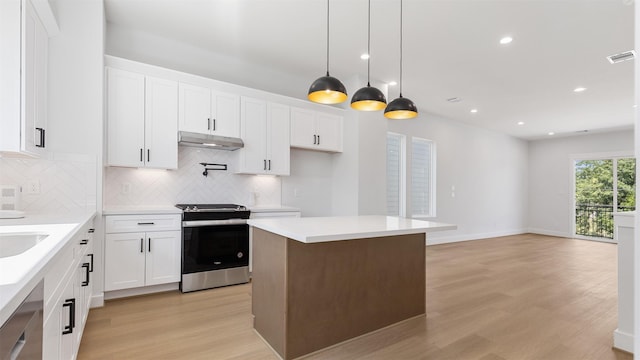 7229 Tierwester St, Houston, TX 77021 - kitchen featuring appliances with stainless steel finishes, under cabinet range hood, light wood-style flooring, tasteful backsplash, and white cabinetry