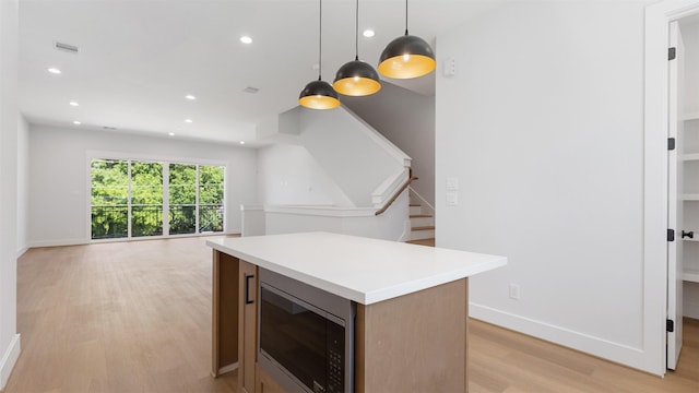 7229 Tierwester St, Houston, TX 77021 - kitchen with stainless steel microwave, light wood finished floors, recessed lighting, a kitchen island, and light countertops