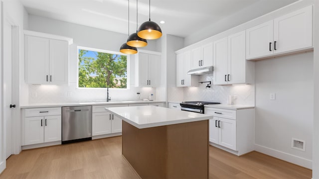 7229 Tierwester St, Houston, TX 77021 - kitchen with appliances with stainless steel finishes, light wood finished floors, decorative backsplash, under cabinet range hood, and white cabinetry