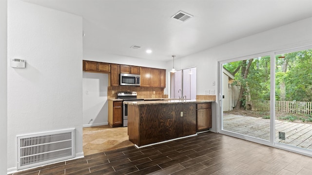 2139 E Settlers Way, The Woodlands, TX 77380 - kitchen with stainless steel appliances, wood tiled floors, a peninsula, backsplash, and decorative light fixtures