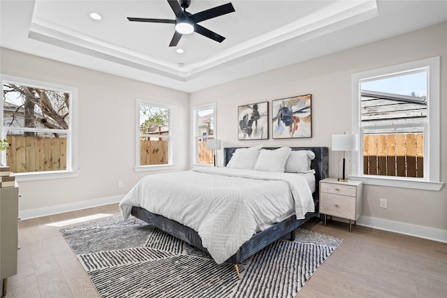 1118 W Cottage St, Houston, TX 77009 - bedroom featuring a tray ceiling, wood finished floors, baseboards, recessed lighting, and a ceiling fan