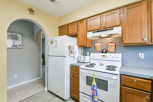 4030 Fort Bend Dr, Galveston, TX 77554 - kitchen featuring white appliances, under cabinet range hood, arched walkways, brown cabinets, and light countertops