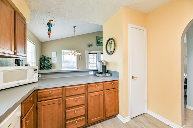 4030 Fort Bend Dr, Galveston, TX 77554 - kitchen with white microwave, brown cabinetry, arched walkways, light wood-style floors, and plenty of natural light