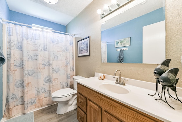 4030 Fort Bend Dr, Galveston, TX 77554 - bathroom with wood finished floors, a textured wall, toilet, vanity, and a shower with shower curtain
