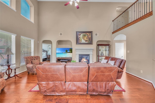 24628 Hosford Meadows Dr, Porter, TX 77365 - living room featuring a ceiling fan, a high ceiling, baseboards, a glass covered fireplace, and wood finished floors