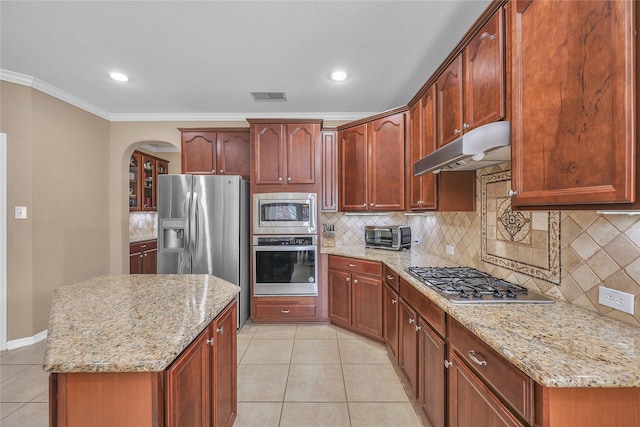 24628 Hosford Meadows Dr, Porter, TX 77365 - kitchen with stainless steel appliances, under cabinet range hood, crown molding, light tile patterned flooring, and tasteful backsplash