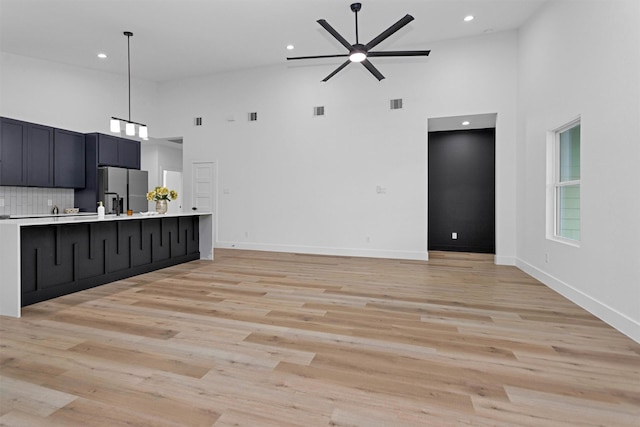 4021 King St, Houston, TX 77026 - unfurnished living room with high vaulted ceiling, ceiling fan, recessed lighting, light wood-style flooring, and baseboards