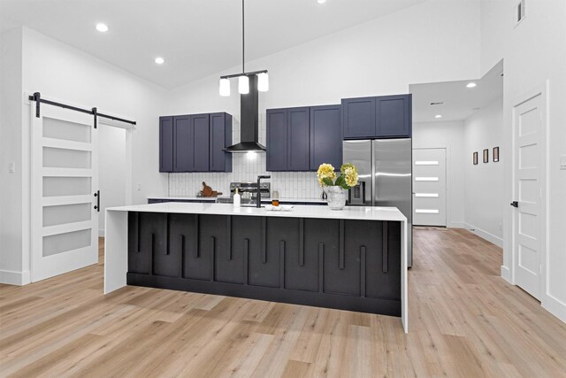 4021 King St, Houston, TX 77026 - kitchen featuring a barn door, light countertops, decorative backsplash, a large island with sink, and a high ceiling