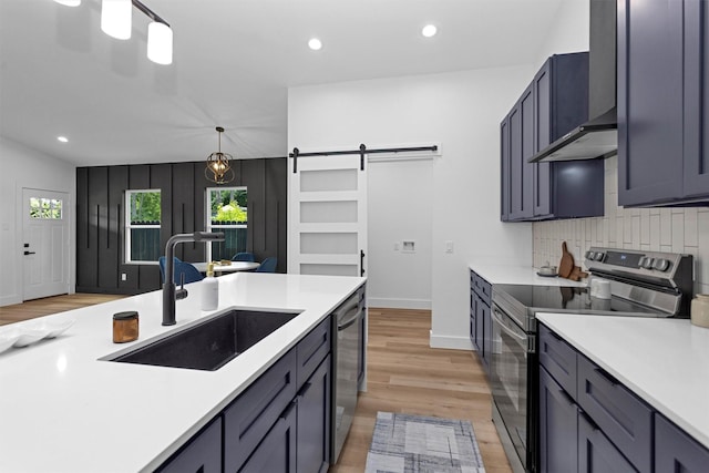 4021 King St, Houston, TX 77026 - kitchen with stainless steel appliances, a sink, a barn door, light countertops, and light wood finished floors