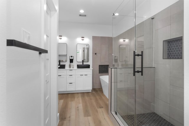 4021 King St, Houston, TX 77026 - full bathroom with wood finished floors, a stall shower, a freestanding tub, double vanity, and recessed lighting