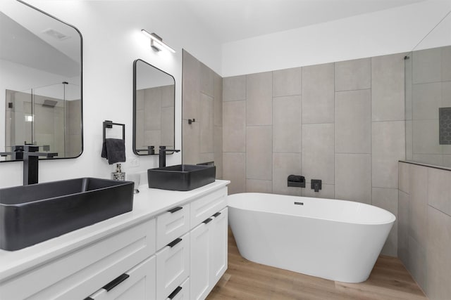4021 King St, Houston, TX 77026 - bathroom featuring wood finished floors, a soaking tub, a shower with shower door, and double vanity