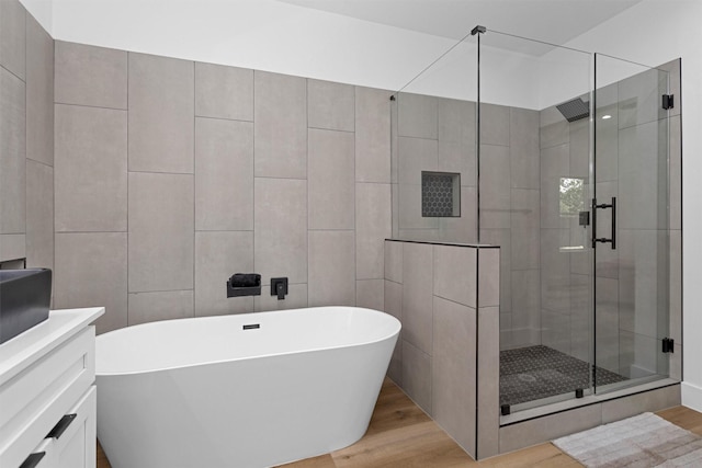 4021 King St, Houston, TX 77026 - bathroom featuring wood finished floors, a stall shower, a freestanding tub, and vanity