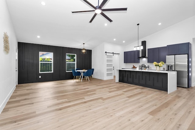 4021 King St, Houston, TX 77026 - kitchen with stainless steel refrigerator with ice dispenser, a barn door, wall chimney exhaust hood, light countertops, and light wood-style flooring