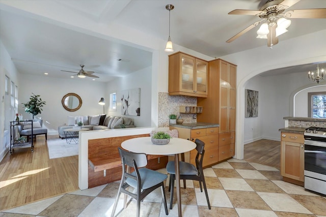 924 E 27th St, Houston, TX 77009 - kitchen featuring ceiling fan, stainless steel range with gas stovetop, arched walkways, backsplash, and glass insert cabinets