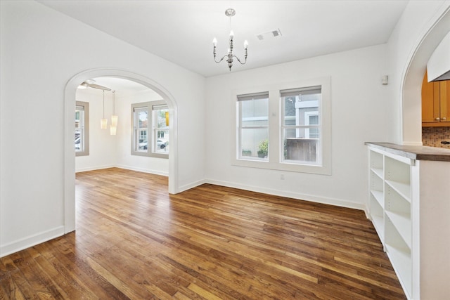 924 E 27th St, Houston, TX 77009 - unfurnished dining area featuring arched walkways, a chandelier, wood finished floors, and baseboards
